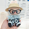 Blue plaid shirt + cuffed blue jeans + khaki flat-brim straw hat + black camera + black-rimmed glasses + white canvas shoes